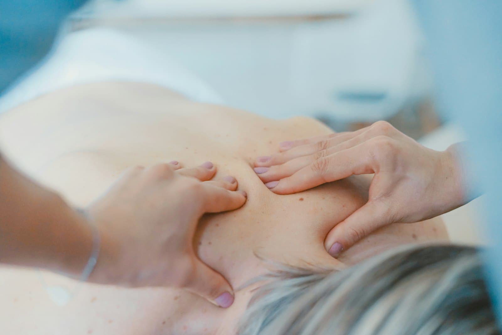 A physiotherapist treating a patient's upper back with hands-on therapy